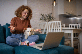 Pet Owner Booking a Home Vet Visit - XCura Mobile Vet Pet owner at home using a laptop while sitting with a dog before a mobile vet visit
